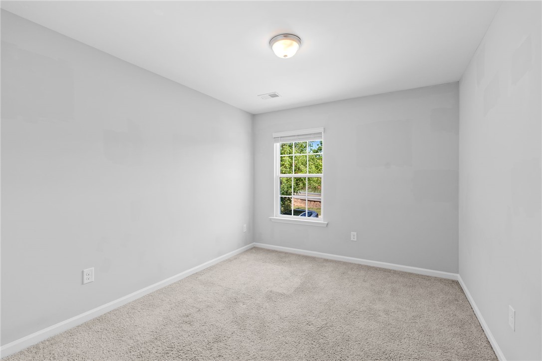 1237 Madden Bridge Road Central, SC 29630 - Photo 35 of 46 This cozy bedroom features plush carpet flooring and a bright window overlooking lush greenery.