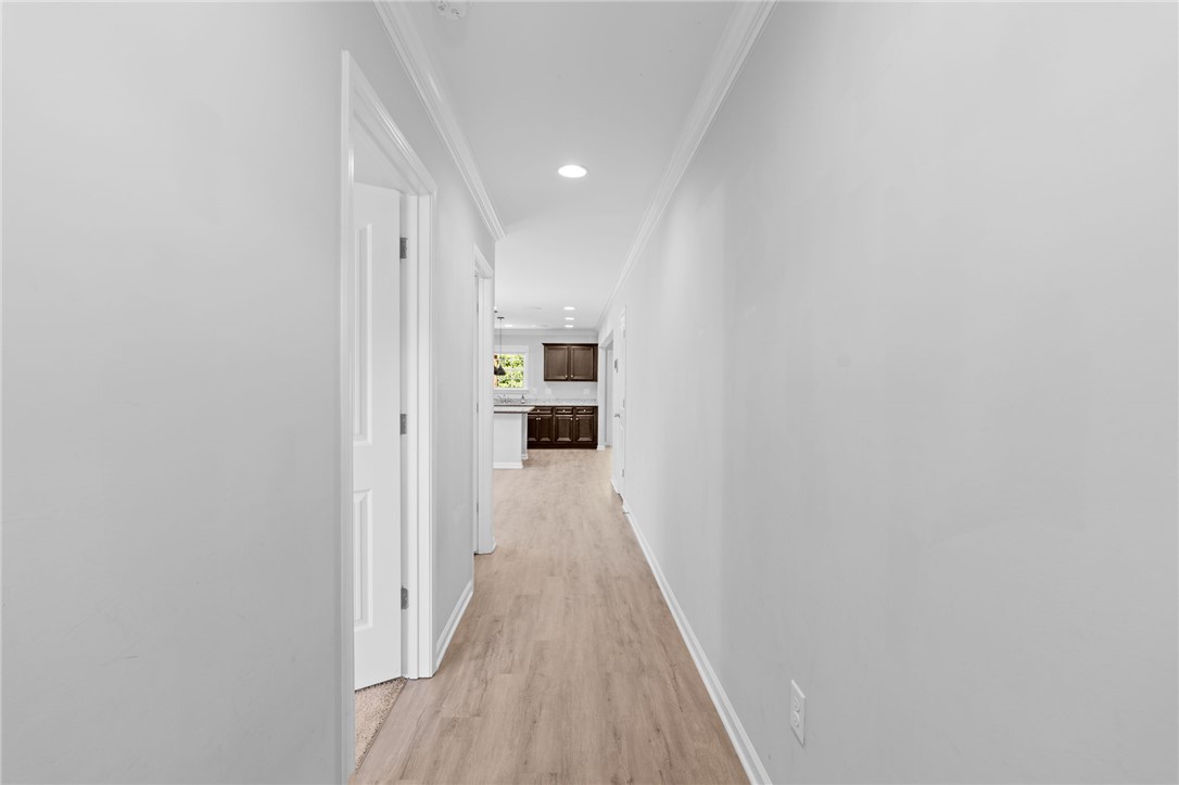 1237 Madden Bridge Road Central, SC 29630 - Photo 6 of 46 A well-lit hallway with light wood flooring leads to a spacious, modern kitchen.