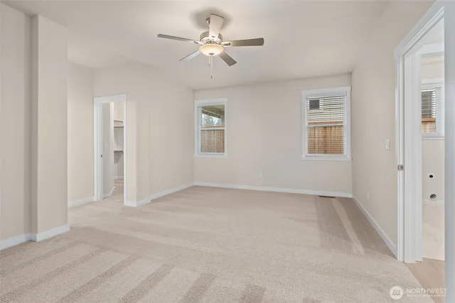 an empty room with chandelier fan and windows