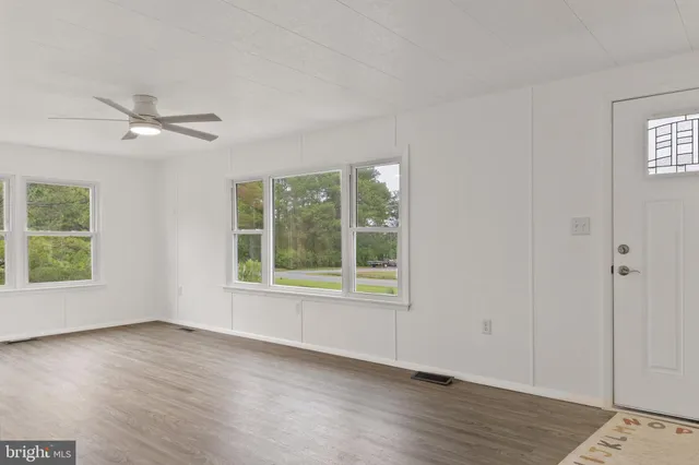 a view of an empty room with a window and wooden floor