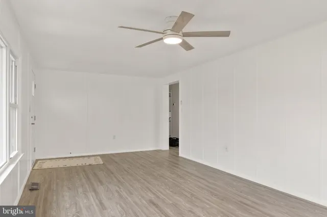 an empty room with wooden floor and a ceiling fan