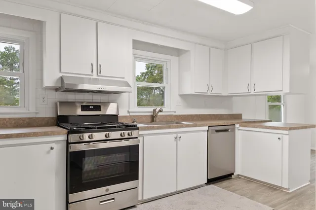 a kitchen with granite countertop white cabinets and appliances