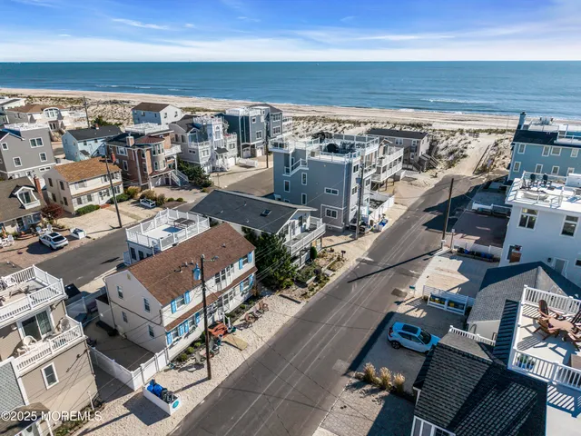 an aerial view of a city with lots of residential buildings and ocean view in back