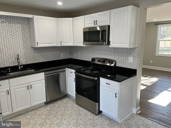 a kitchen with granite countertop white cabinets and black appliances