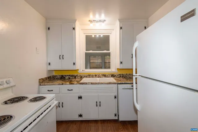 a kitchen with a refrigerator a stove a sink and a wooden floor