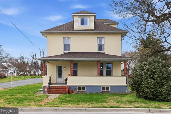 a view of a house with a yard chairs and a large tree