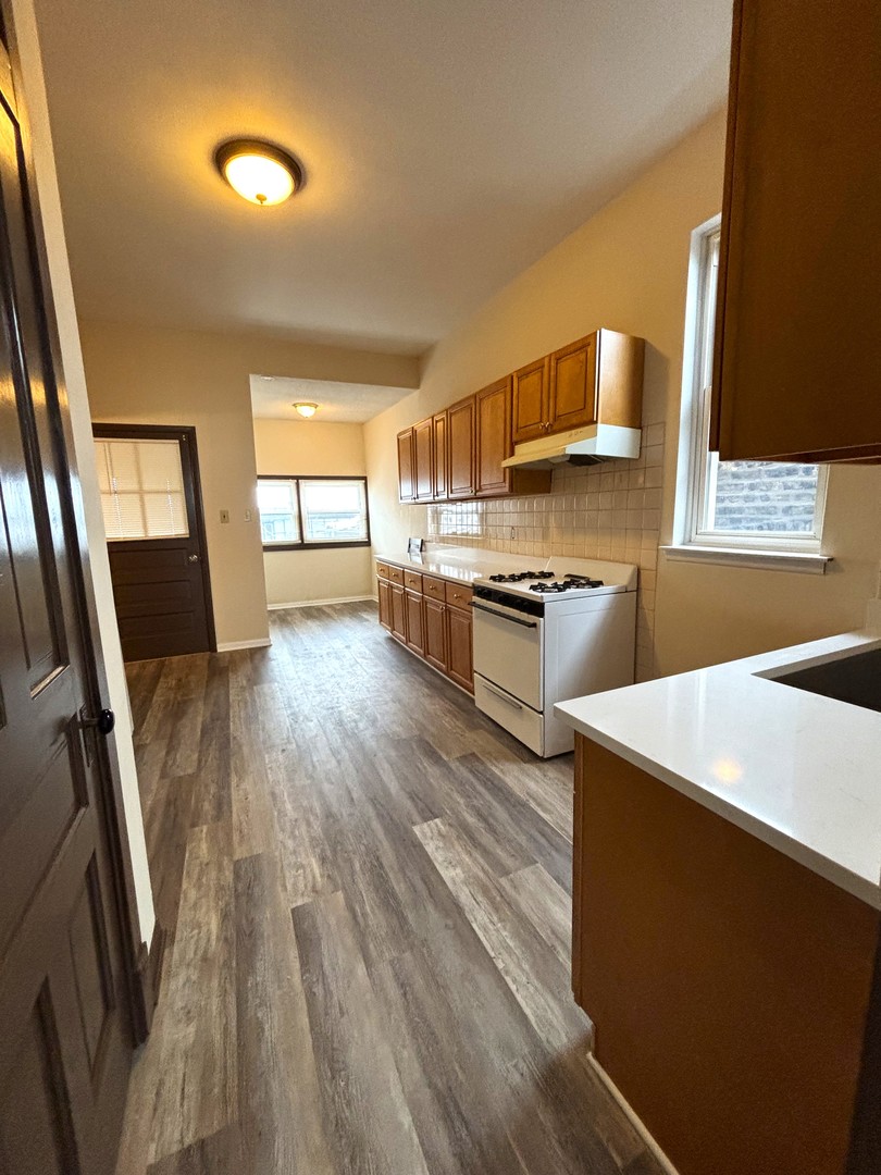 3003 North Ashland Avenue, Unit 3 Chicago, IL 60657 - Photo 10 of 14 a kitchen with stainless steel appliances a stove a sink a refrigerator wooden floor and a dining table