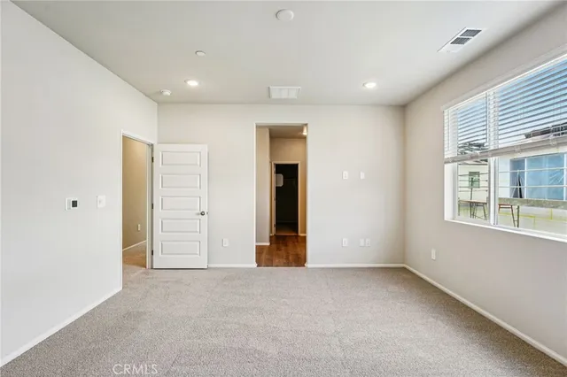 a view of an empty room with wooden floor and windows