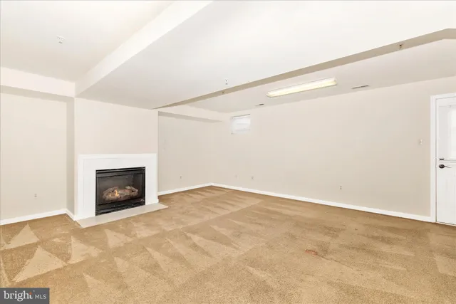 a view of an empty room with fire place and a window