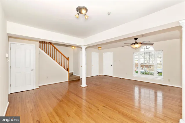a view of an empty room with wooden floor and a window