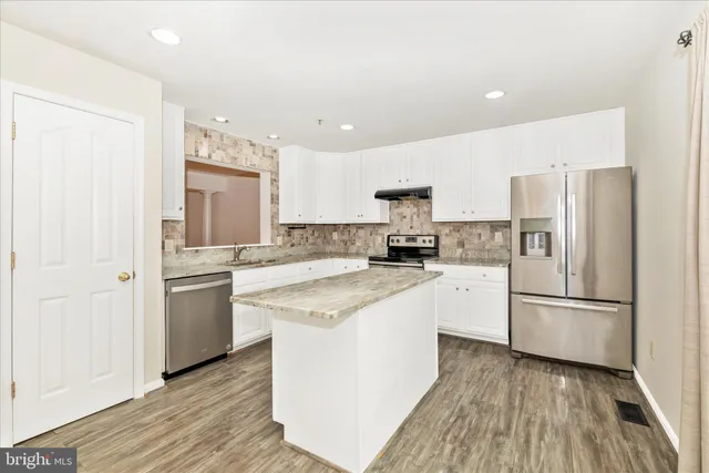 a kitchen with white cabinets and stainless steel appliances
