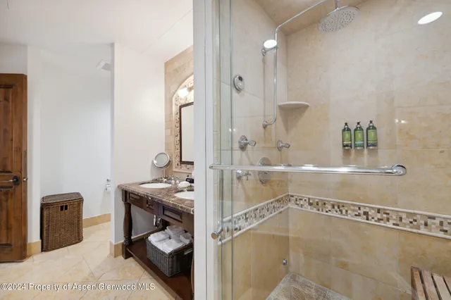 a bathroom with a granite countertop sink a mirror and shower