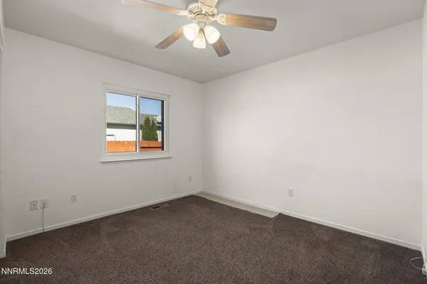an empty room with a window and a fan