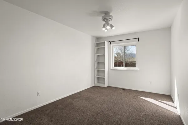 en empty room with windows and chandelier fan