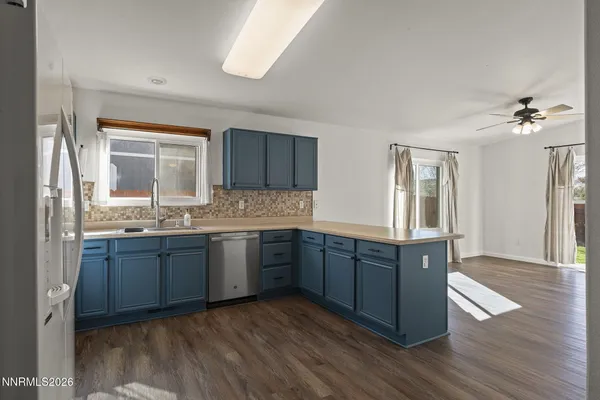 a kitchen with stainless steel appliances granite countertop wooden cabinets a sink a stove a dining table and chairs