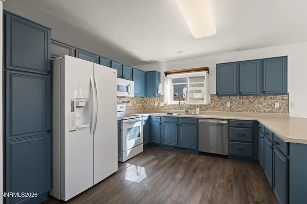a kitchen with granite countertop a refrigerator stove top oven and sink