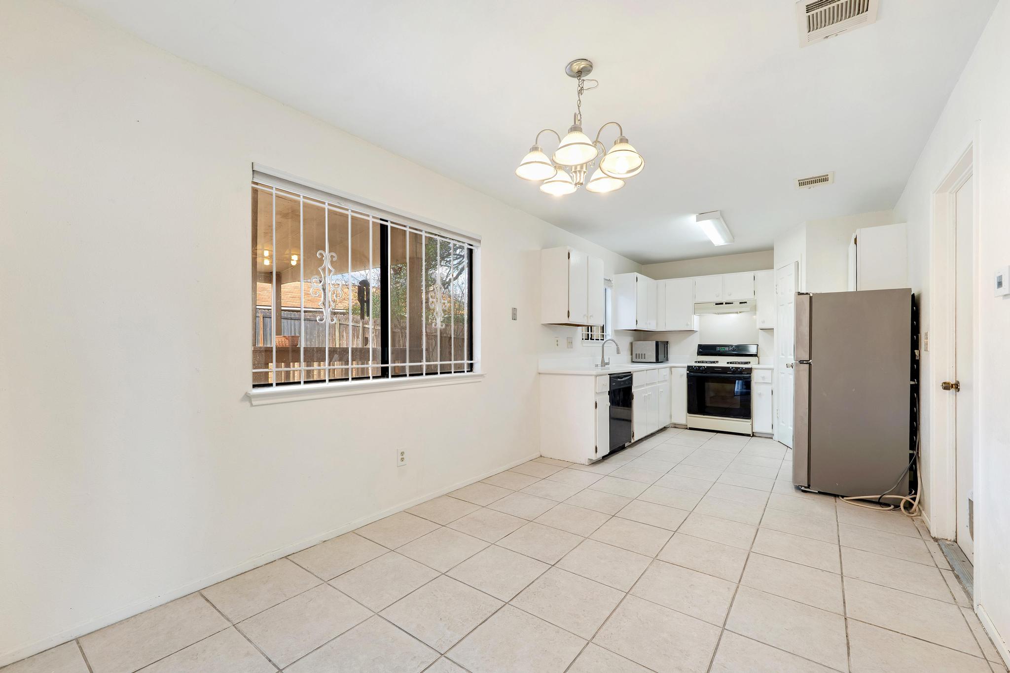 11918 Snow Finch Road Austin, TX 78758 - Photo 12 of 33 Kitchen featuring light countertops, range, freestanding refrigerator, a chandelier, and white cabinetry