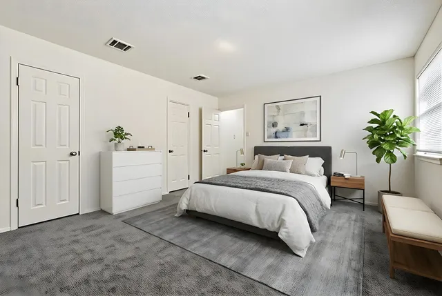 a spacious bedroom with a bed and a plant