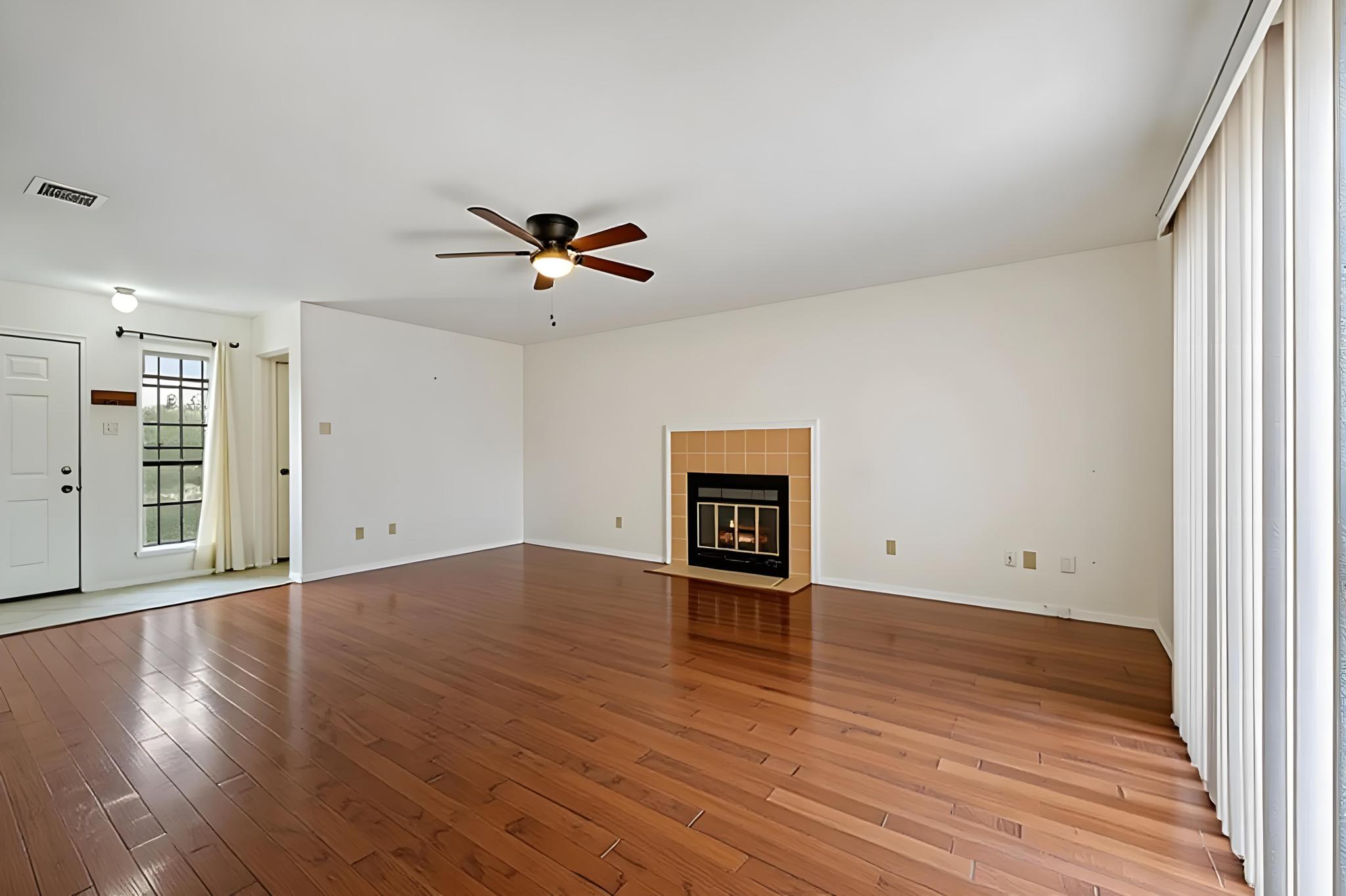 11918 Snow Finch Road Austin, TX 78758 - Photo 7 of 33 Unfurnished living room with a tiled fireplace, light wood-style floors, and ceiling fan