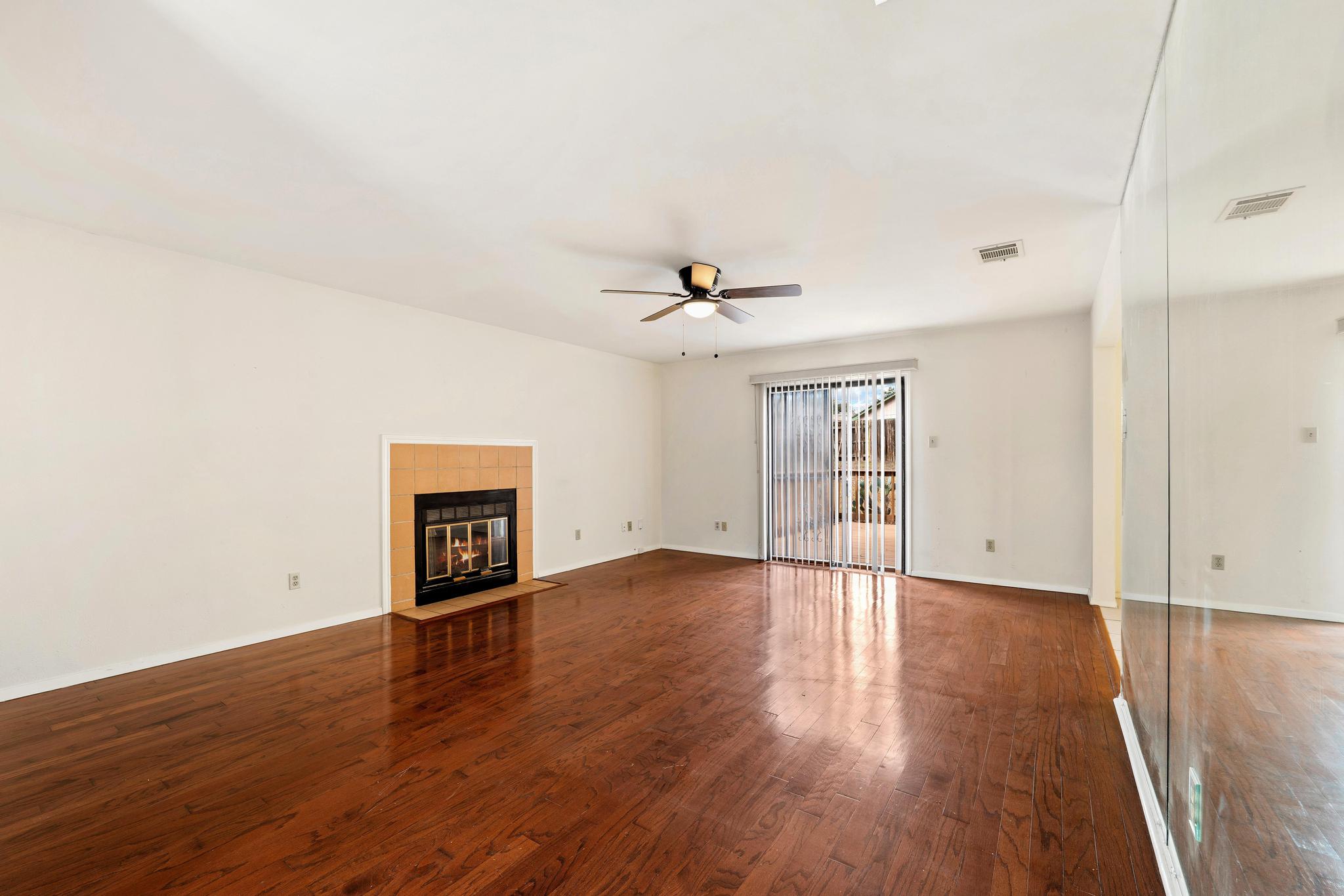 11918 Snow Finch Road Austin, TX 78758 - Photo 9 of 33 Unfurnished living room with dark wood-style floors, a tiled fireplace, and ceiling fan
