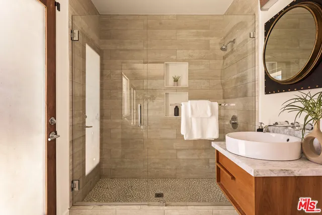 a bathroom with a granite countertop shower a mirror and a sink