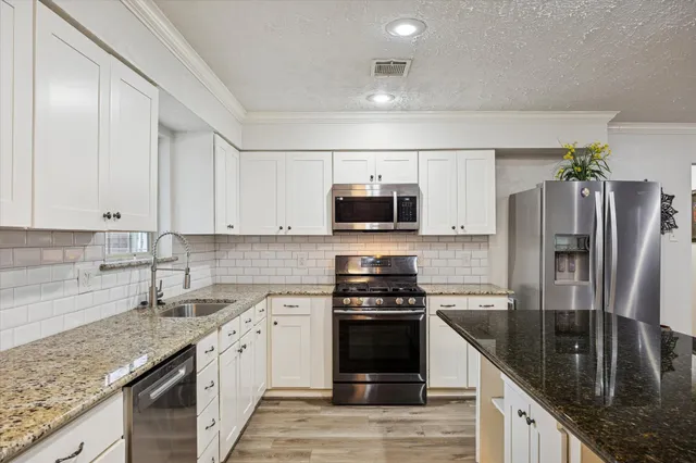 a kitchen with stainless steel appliances granite countertop a sink stove and refrigerator