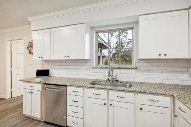 a kitchen with granite countertop white cabinets and a window
