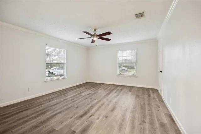 an empty room with wooden floor and windows