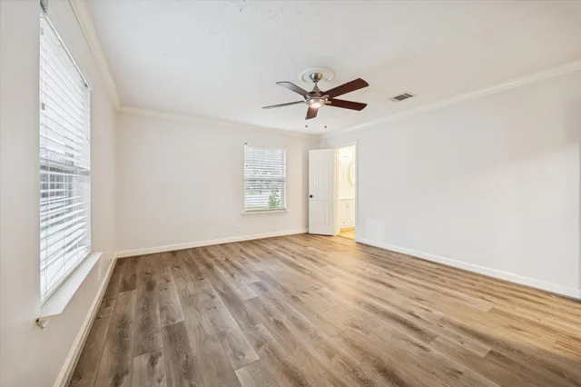 a view of empty room with wooden floor and fan