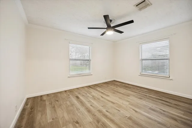 a view of empty room with wooden floor and fan