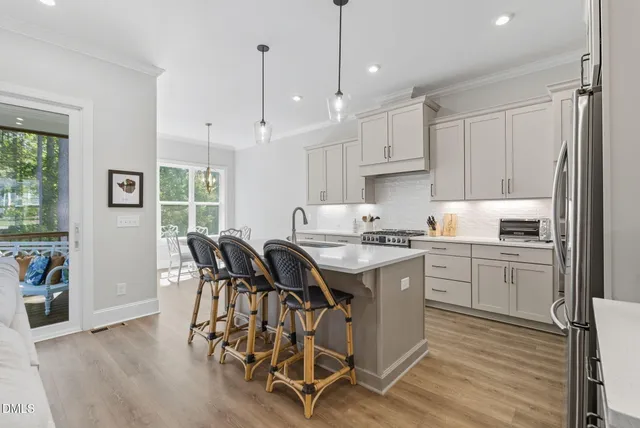 a large white kitchen with a stove a sink a refrigerator and a living room view