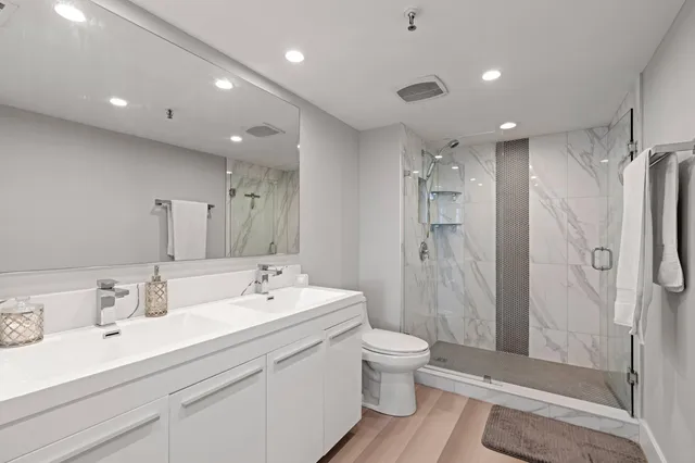 a bathroom with a double vanity sink toilet and shower