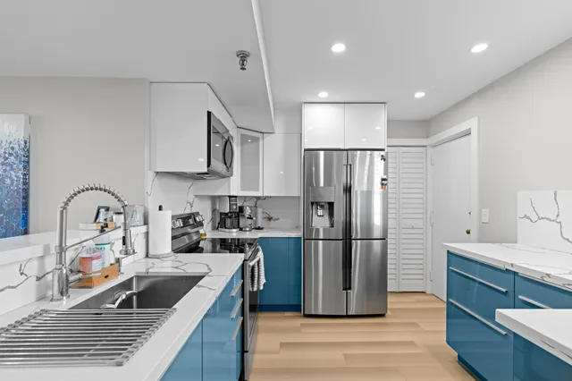a kitchen with stainless steel appliances granite countertop a refrigerator sink and wooden cabinets