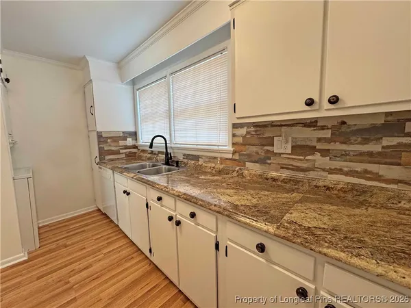 a kitchen with granite countertop a sink and a wooden floor