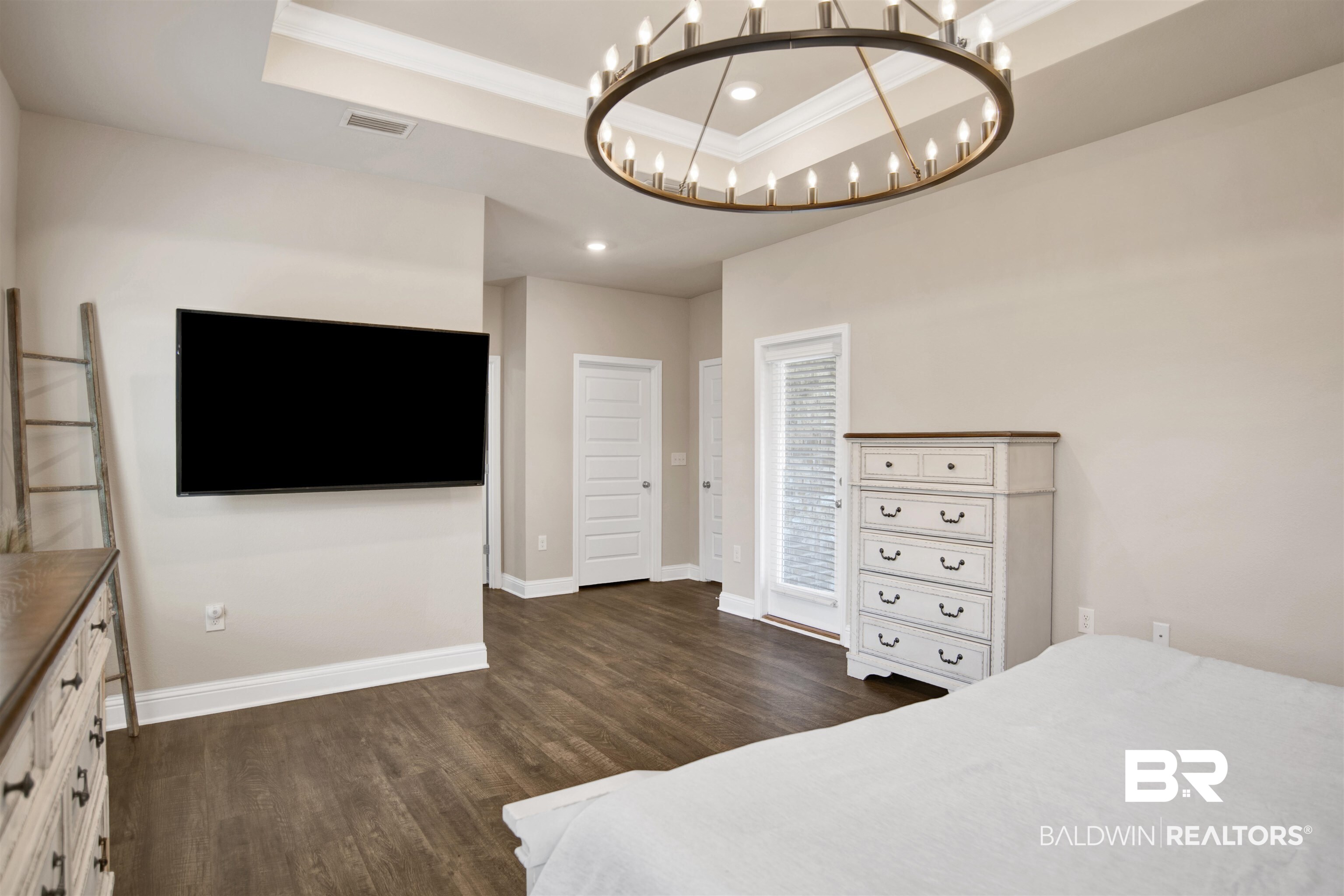 8493 Bronze Lane Foley, AL 36535 - Photo 19 of 38 Spacious interior featuring wood-finish flooring, a tray ceiling with crown molding, and a modern circular chandelier