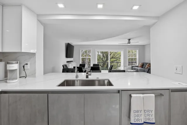 a kitchen with a sink a counter top space and living room area