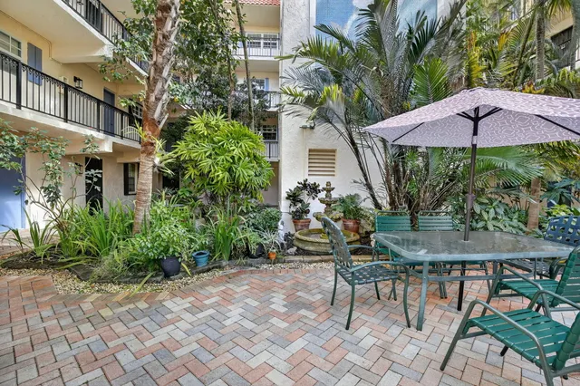 a backyard of a house with table and chairs under an umbrella