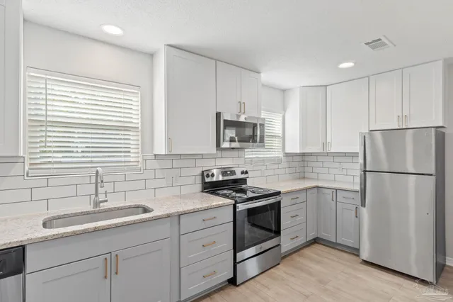 a kitchen with a sink white cabinets and white appliances