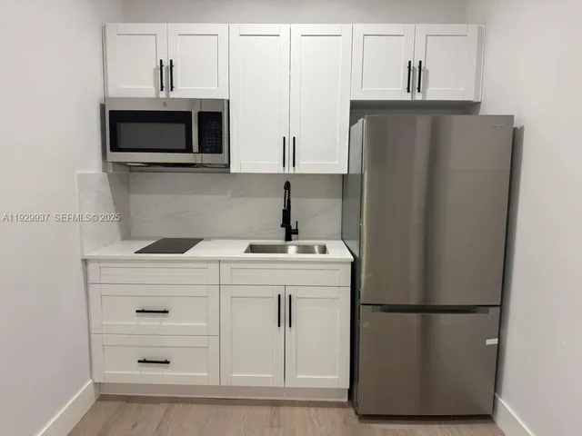 a kitchen with a refrigerator sink and cabinets