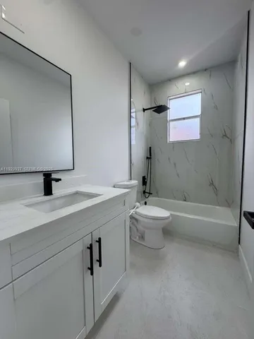 a bathroom with a granite countertop sink a toilet and a bathtub