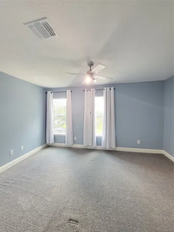 a view of a big room with windows and chandelier fan