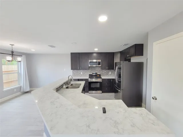 a large kitchen with stainless steel appliances kitchen island a stove a refrigerator a oven and a sink with large countertops