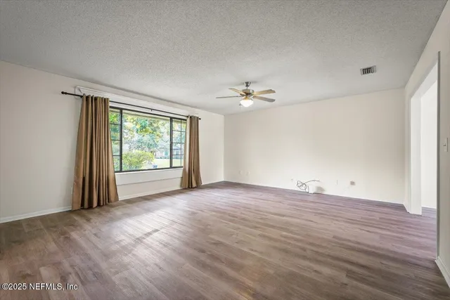 a view of empty room with wooden floor and ceiling fan