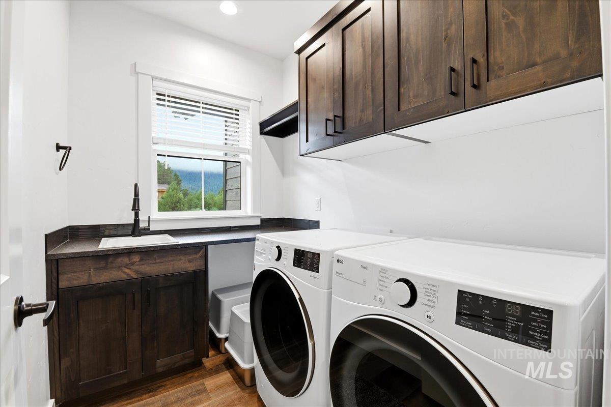 13152 Hawks Bay Road Donnelly, ID 83615 - Photo 24 of 29 Laundry room featuring dark wood-finish cabinetry, a black countertop, and a utility sink with a matte black faucet