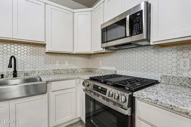 a kitchen with stainless steel appliances granite countertop cabinets and a stove top oven