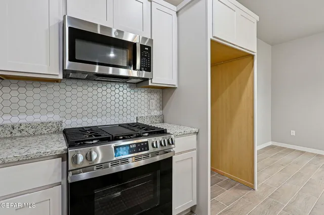 a kitchen with stainless steel appliances granite countertop cabinets and a stove top oven