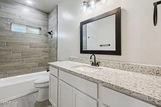 a bathroom with a granite countertop toilet sink and mirror
