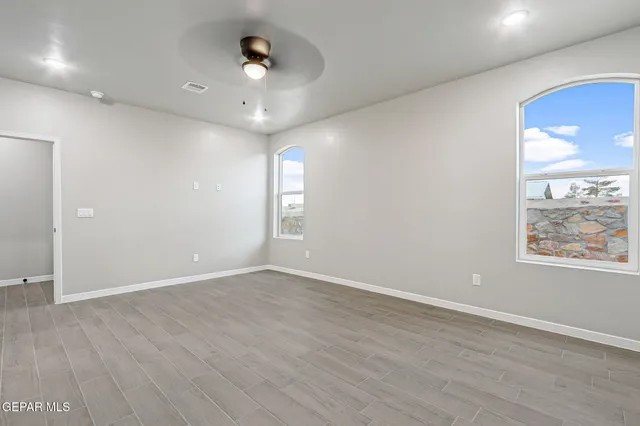 an empty room with wooden floor and windows