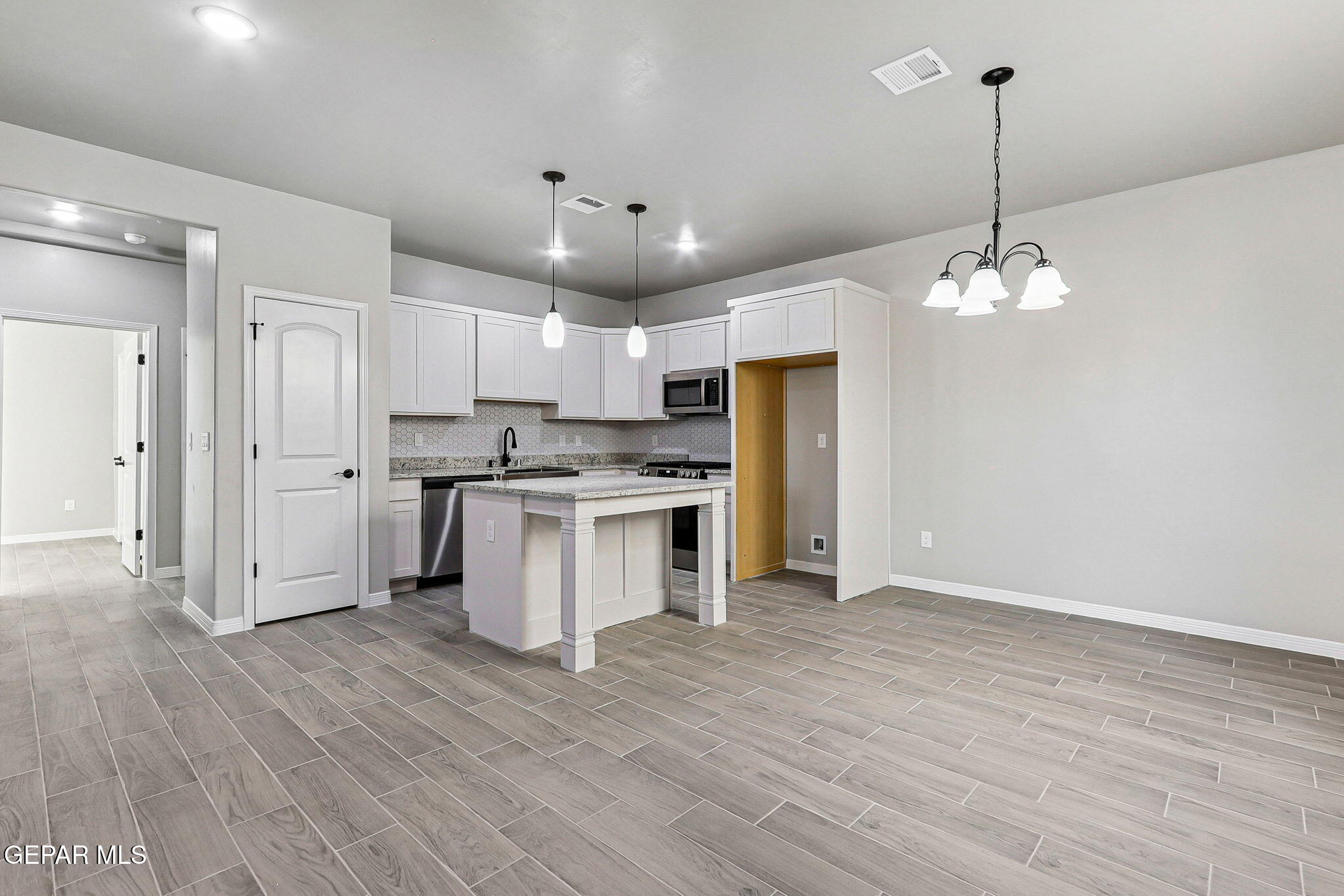 1153 Marquitos Avenue Anthony, NM 88021 - Photo 6 of 40 a kitchen with stainless steel appliances granite countertop a refrigerator a sink dishwasher a stove and white cabinets with wooden floor