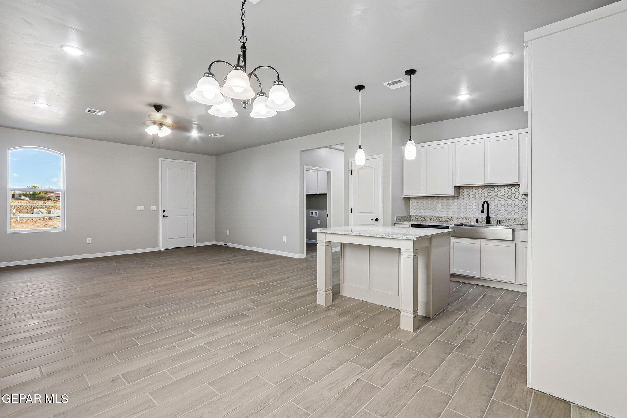 1153 Marquitos Avenue Anthony, NM 88021 - Photo 9 of 40 a large kitchen with granite countertop a stove a sink and white cabinets with wooden floor